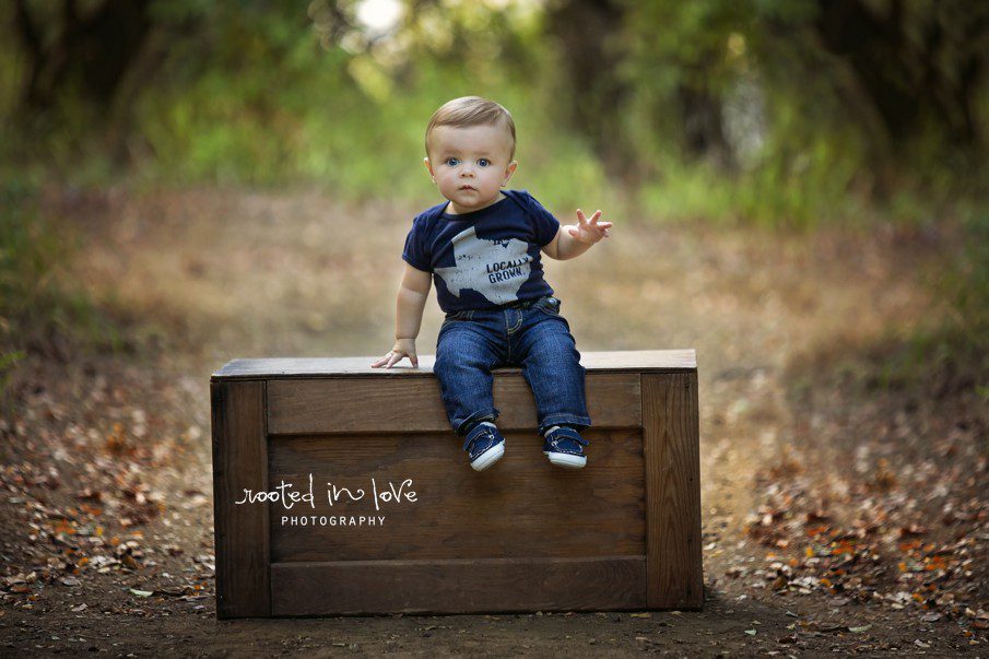 Baby boy sitting on a wooden box.