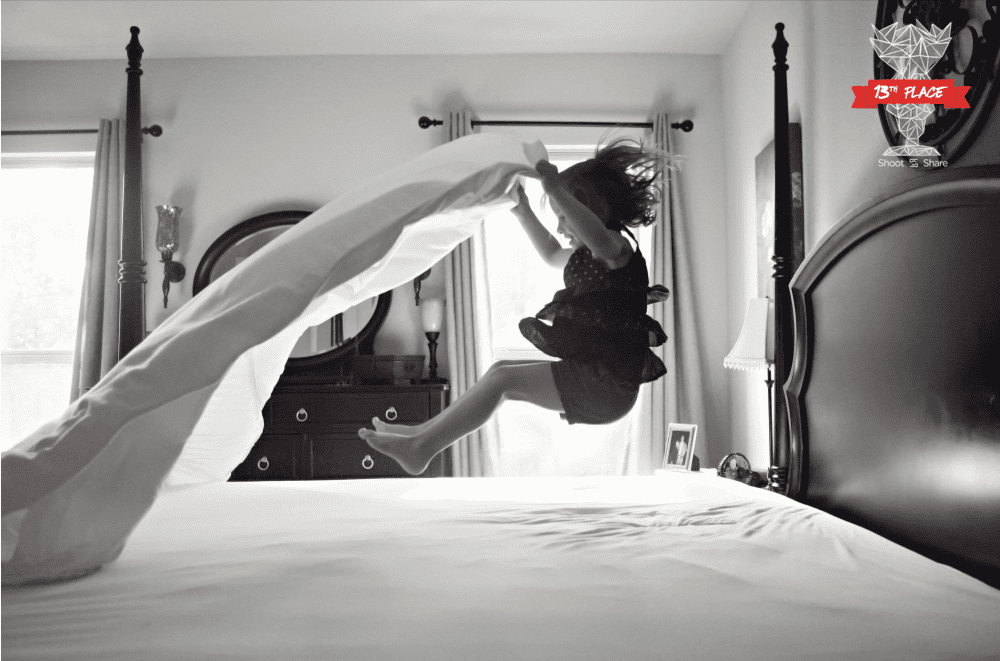 Girl jumping on bed with sheet.