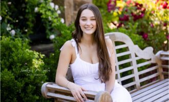 Smiling woman in white dress on bench.